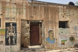 Image of a building with bullet holes strewn on the walls.